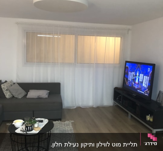 סלון עם שולחן קטן, ספה וטלוויזיה דולקת